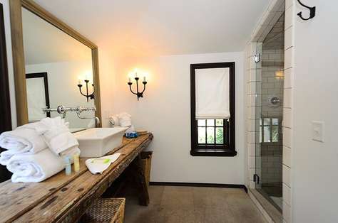 Master bathroom with antique farm table serving as the counter, large walk in shower with dual rain shower heads