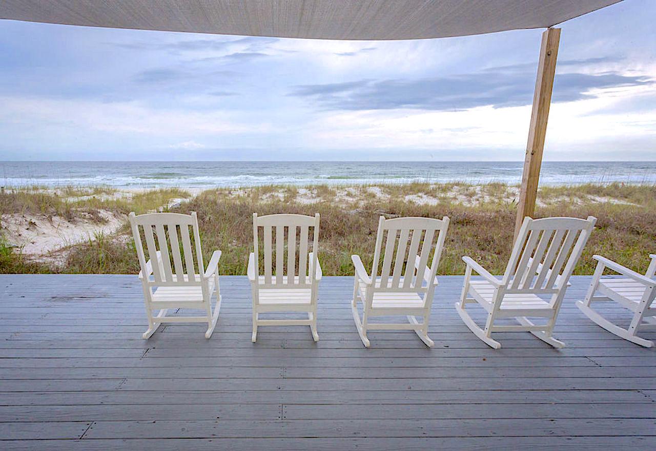 Large back deck with rockers and sun screen overlooking the ocean