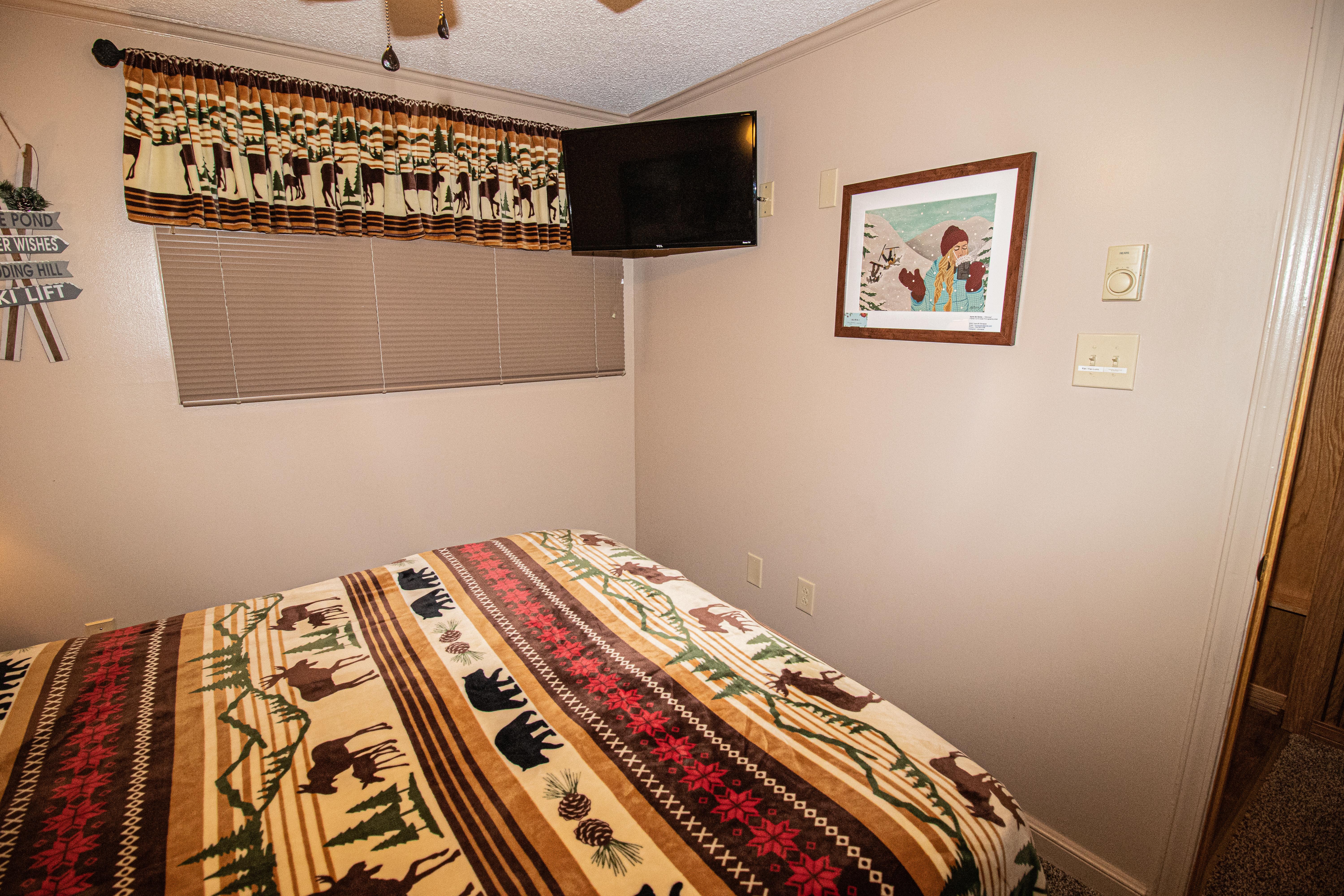 Queen size bed, TV, & ceiling fan in comfy bedroom
