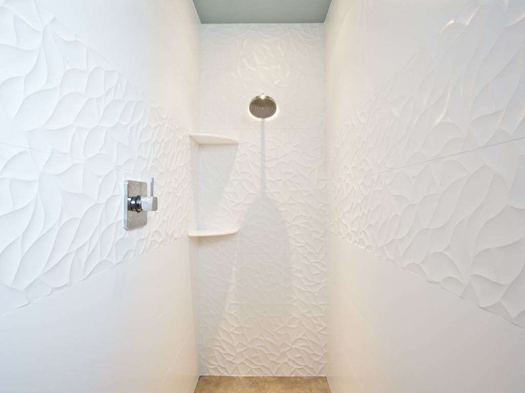 Beautiful tiles line the walls to the walk in shower with radiant heated floor.