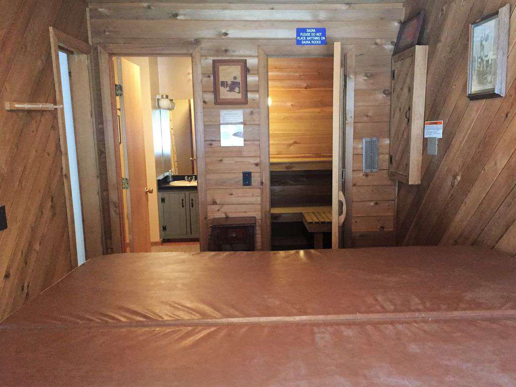hot tub room (hot tub covered in foreground) with sauna and bathroom