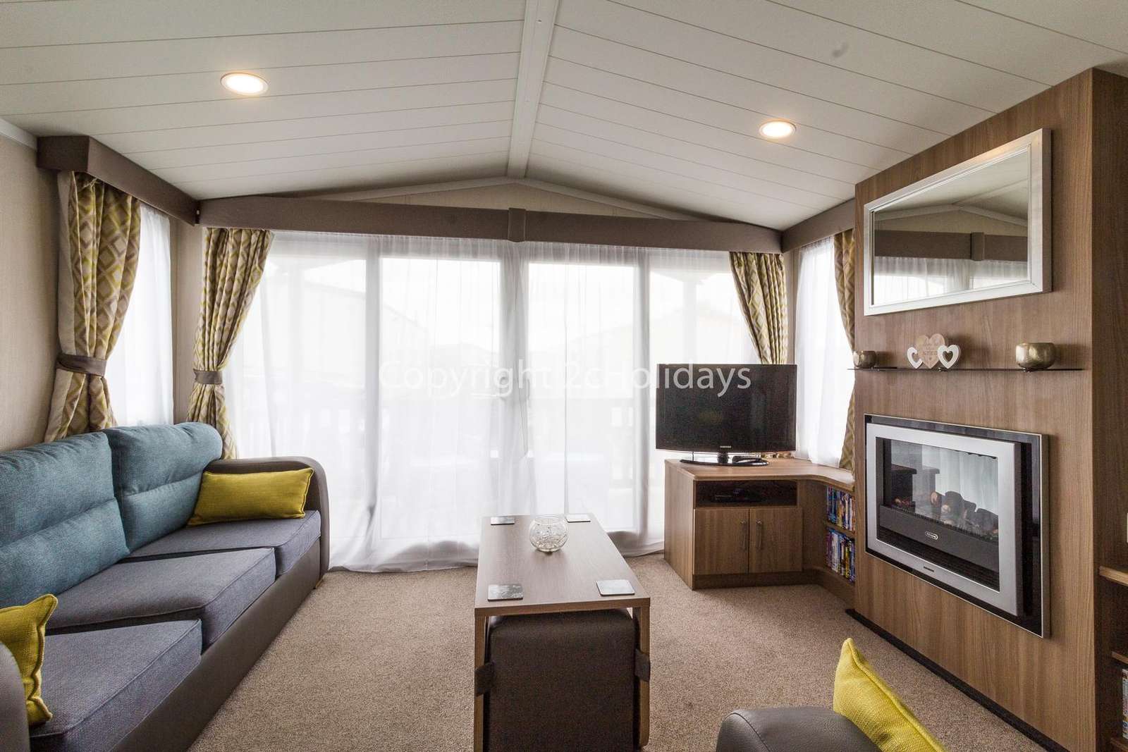 A very modern living area with a double sofa bed, TV and electric fireplace