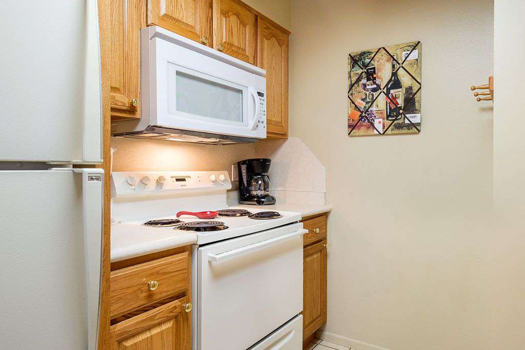 Kitchen side view including microwave, gas stove, and coffee maker
